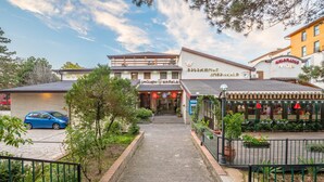A hotel entrance with a paved pathway leading to the door, surrounded by greenery and a fence. - Kopala Tskneti (Tbilisi)