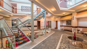 A spacious lobby with a central staircase, multiple seating areas, and a decorative vase on a round table. - Kopala Tskneti (Tbilisi)