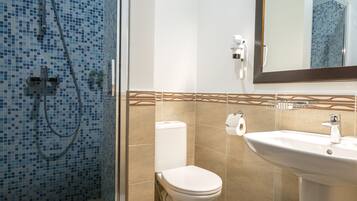 A bathroom with a glass-enclosed shower, a toilet, and a sink with a mirror above it.