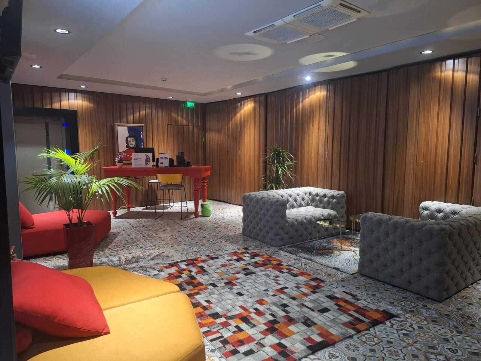 Un hall d’entrée moderne avec un comptoir d’accueil, un espace salon comprenant des canapés et des fauteuils, et un tapis à motifs.