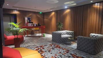 Un hall d’entrée moderne avec un comptoir d’accueil, un espace salon comprenant des canapés et des fauteuils, et un tapis à motifs.