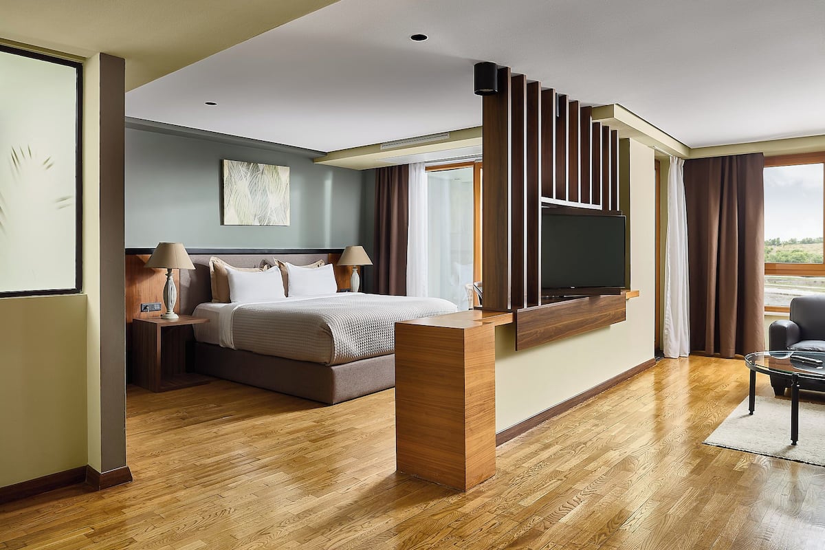 Ein modernes Hotelzimmer mit einem großen Bett, einem wandmontierten Flachbildfernseher und einem Holztisch.
