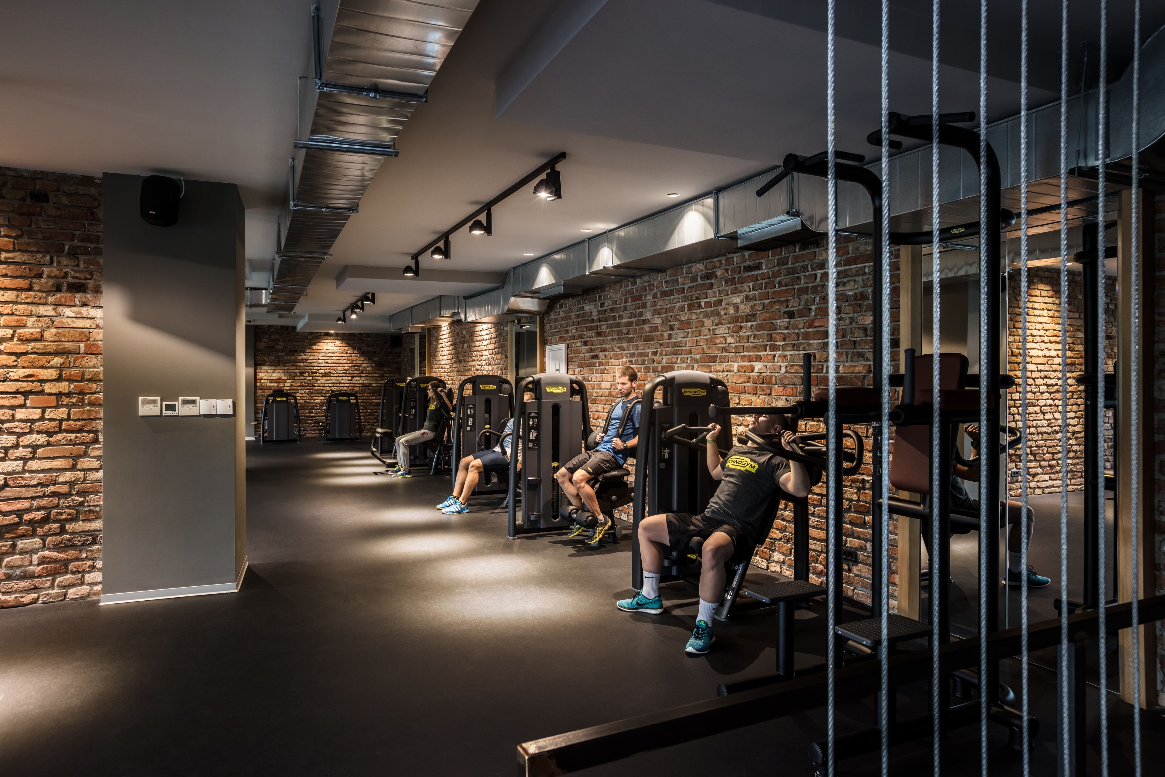 Un gimnasio con paredes de ladrillo, equipo de ejercicio y suelo pulido.