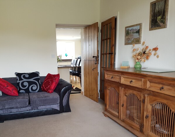 A living room with a grey sofa, wooden cabinet, and a painting on the wall. - Pantysgyfarnog (Carmarthen)