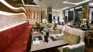 Un restaurante moderno con un banco acolchado rojo, mesas para comer con manteles individuales negros y un diseño de interiores contemporáneo.