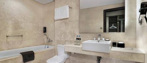 A modern bathroom with a bathtub, toilet, and vanity with a mirror.
