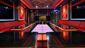 Un interior moderno con una zona de estar central, detalles en rojo y un diseño geométrico en el techo.