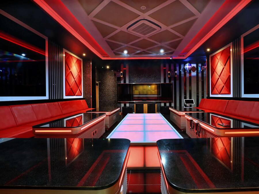 Un interior moderno con una zona de estar central, detalles en rojo y un diseño geométrico en el techo.
