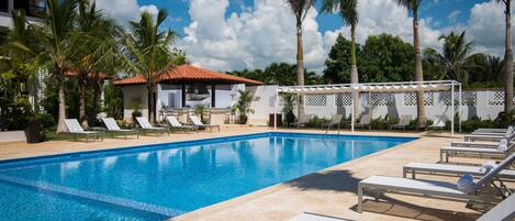 A swimming pool with lounge chairs and palm trees.