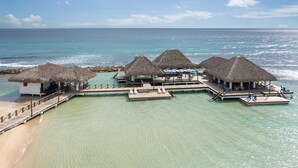 An overwater bungalows with thatched roofs, connected by walkways, and overlooking turquoise waters. - Hotel Casa Hemingway (Guayacanes)