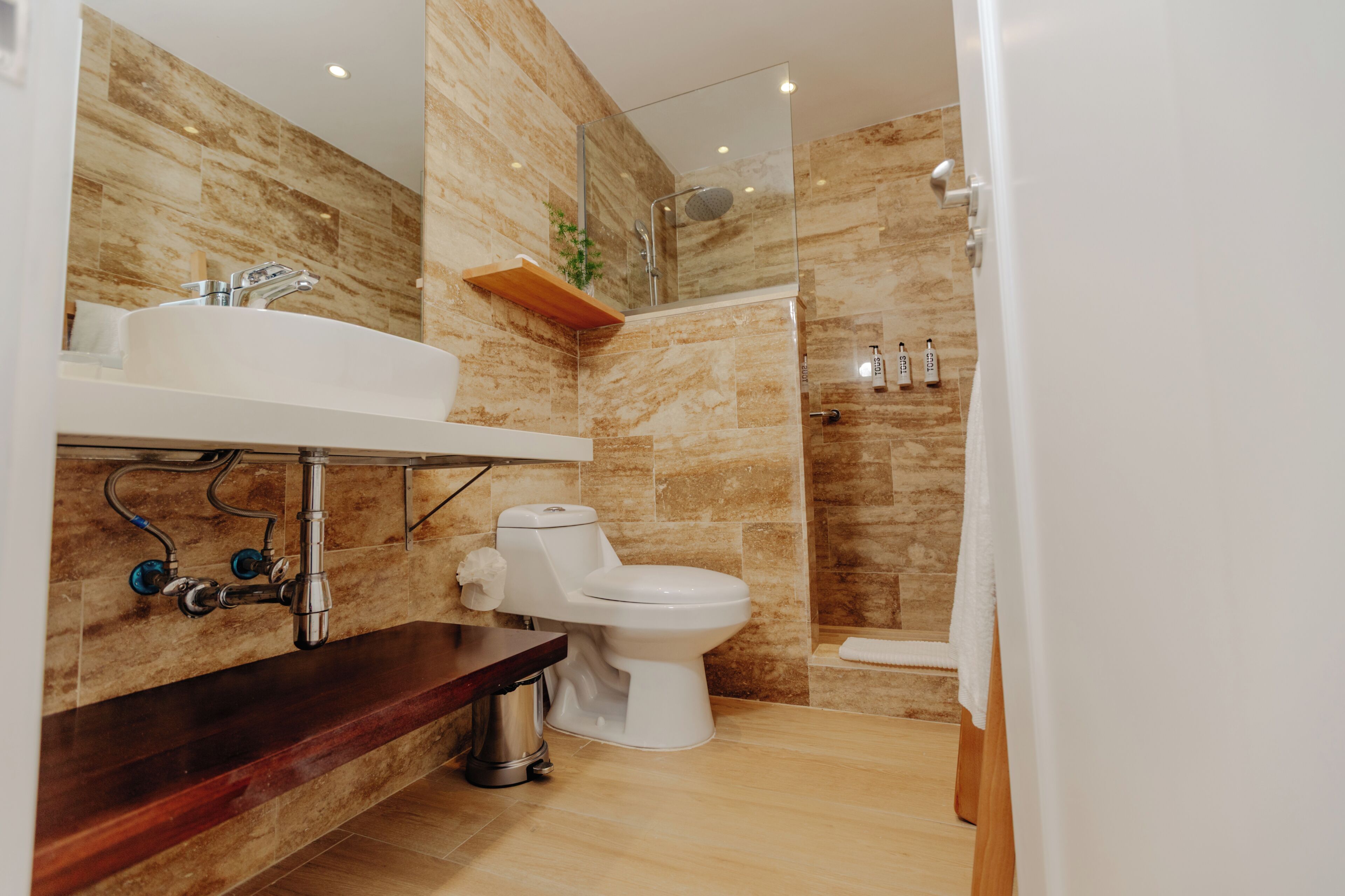 Une salle de bain moderne avec un mur en marbre, un lavabo blanc, des toilettes et un espace douche.