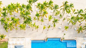 An aerial view of a resort with a swimming pool, palm trees, and a beach. - Hotel Casa Hemingway (Guayacanes)