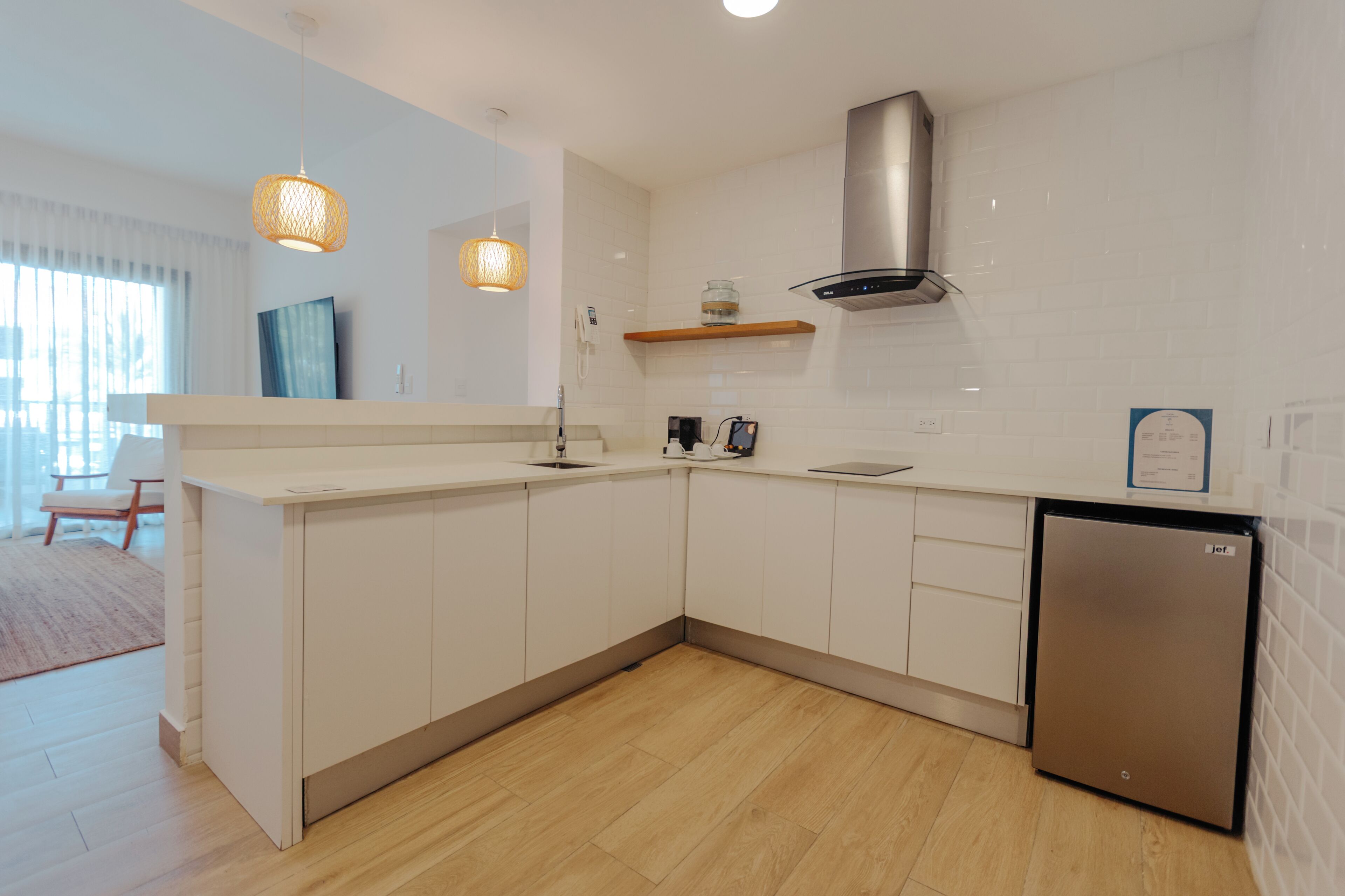 A modern kitchen with white cabinetry, a stainless steel range hood, and a built-in dishwasher.