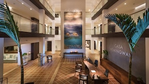 A spacious lobby with a high ceiling, a large mural, and a reception desk. - Hotel Casa Hemingway (Guayacanes)