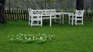 A white wooden bench and table set in a grassy area with trees and a wooden fence in the background.