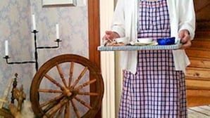 A person in a checkered apron and white shawl holding a tray.
