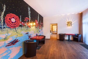 Un vestíbulo de hotel moderno con un gran mural abstracto, suelo de madera y muebles contemporáneos.