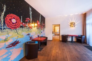 Un hall d’hôtel moderne, agrémenté d’une grande fresque murale abstraite, d’un parquet en bois et de mobilier contemporain.