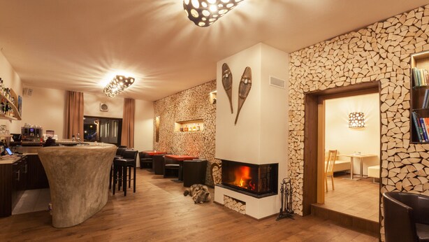 A cozy bar area with a fireplace, wooden flooring, and a stone wall. - Residence AlpenHeart (Bad Gastein)