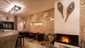 A modern interior with a fireplace, stone wall, and a bar area. - Residence AlpenHeart (Bad Gastein)