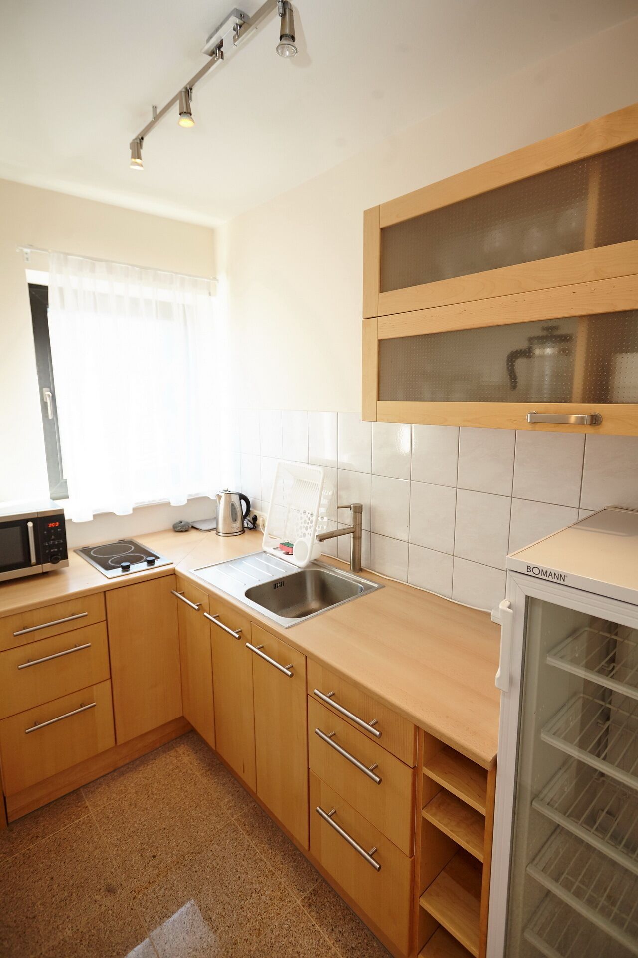 Eine Küche mit Holzausstattung, einer Edelstahlspüle, einer Mikrowelle und einem Kühlschrank.