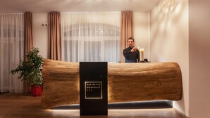 A reception desk with a wooden design, a potted plant, and a sign reading "Residence AlpenHeart". - Residence AlpenHeart (Bad Gastein)