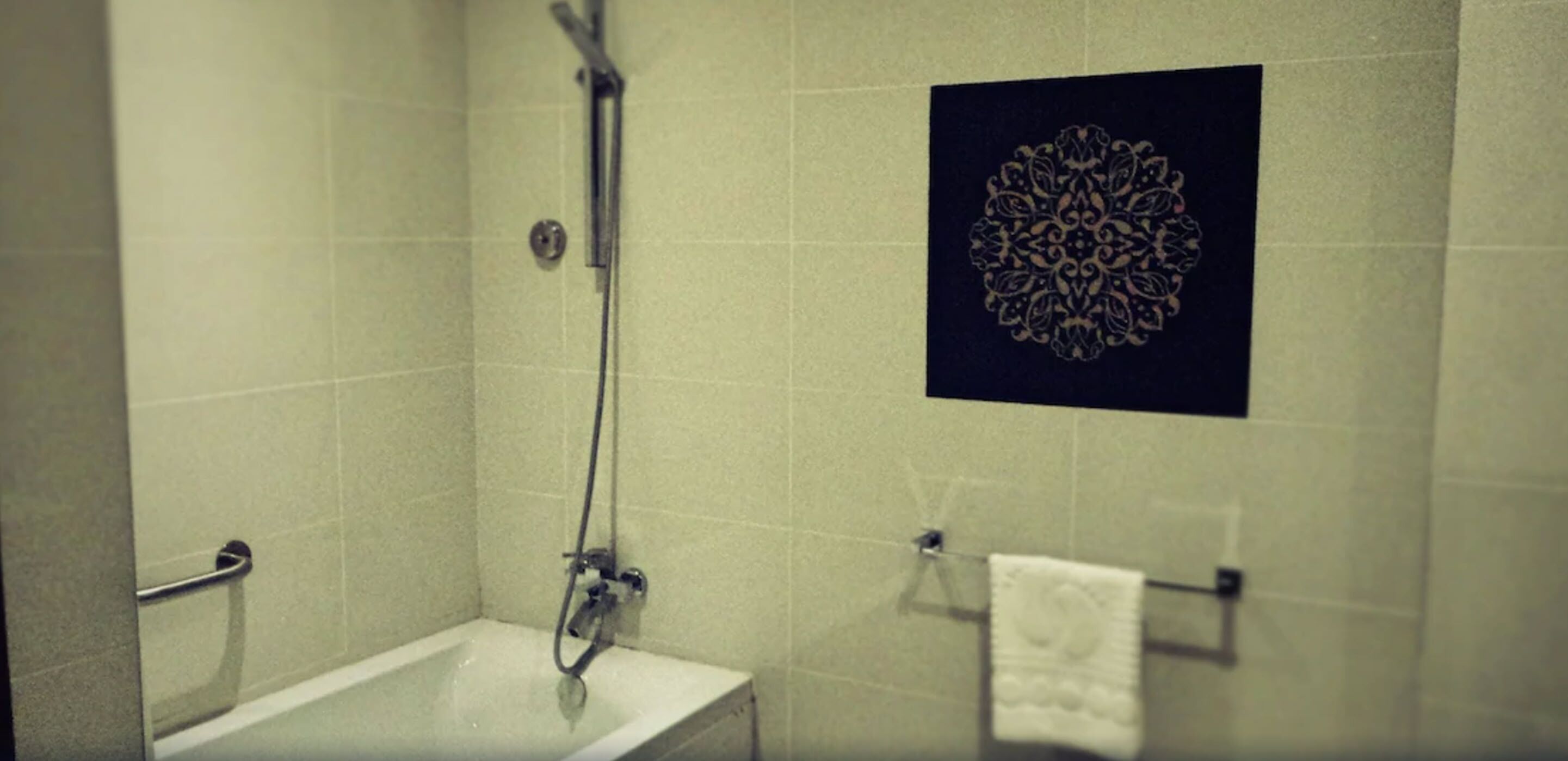 Een badkamer met een douche, een wastafel en een handdoekrek.