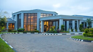 A modern hotel with a large glass facade, a covered entrance, and a landscaped driveway. - Grand Palace Hotel (Mzuzu)
