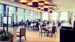 A spacious hotel lobby with multiple dining areas, large windows, and modern lighting fixtures. - Grand Palace Hotel (Mzuzu)