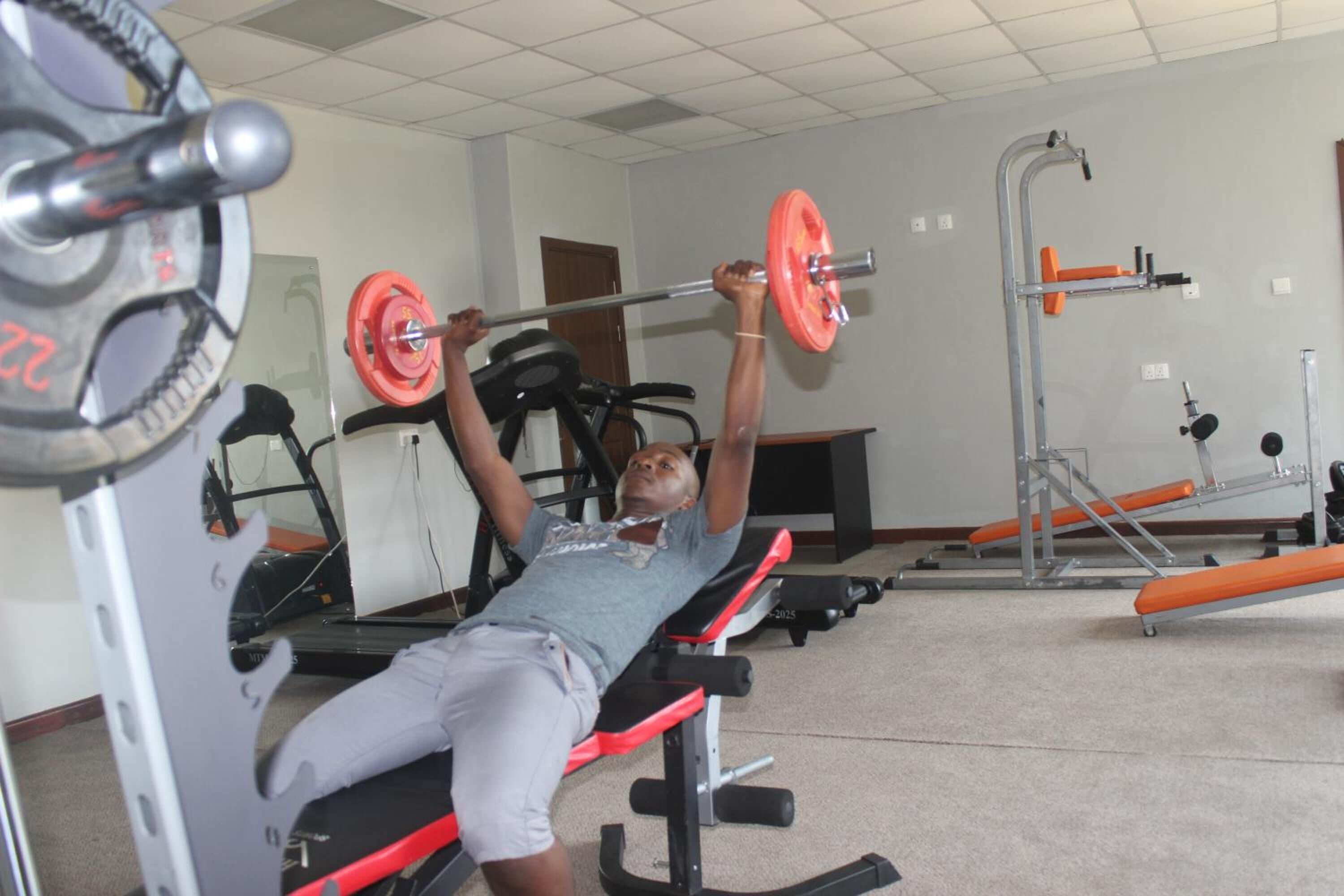 A gym with a bench press, a squat rack, and a bench press with a barbell.