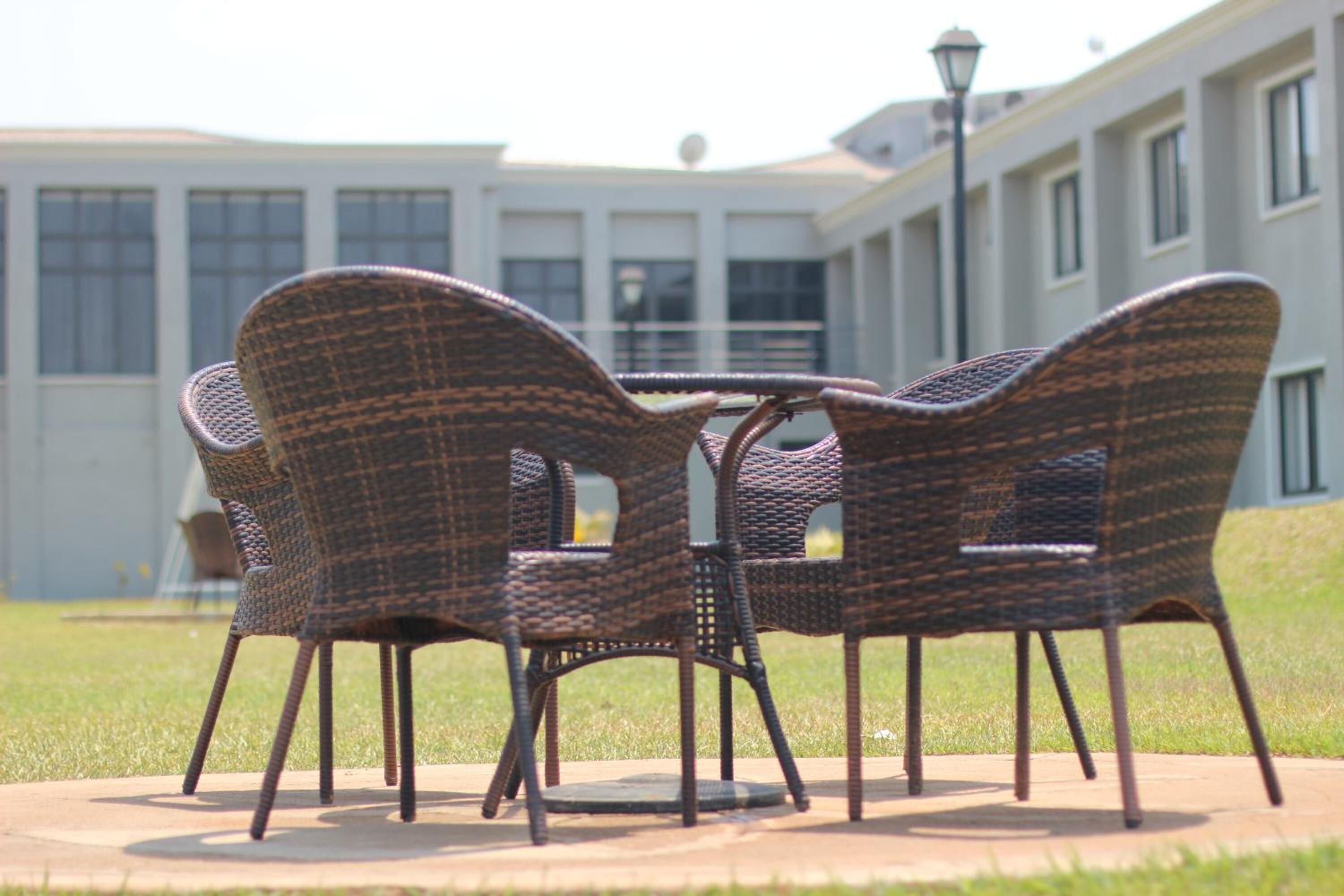 Sillas de mimbre dispuestas alrededor de una mesa en un patio, con un edificio al fondo.