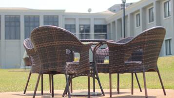 Sillas de mimbre dispuestas alrededor de una mesa en un patio, con un edificio al fondo.