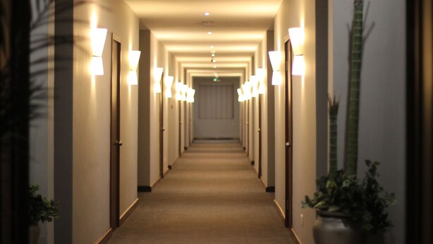 A hotel hallway with multiple doors, each with a light fixture above. - Grand Palace Hotel (Mzuzu)