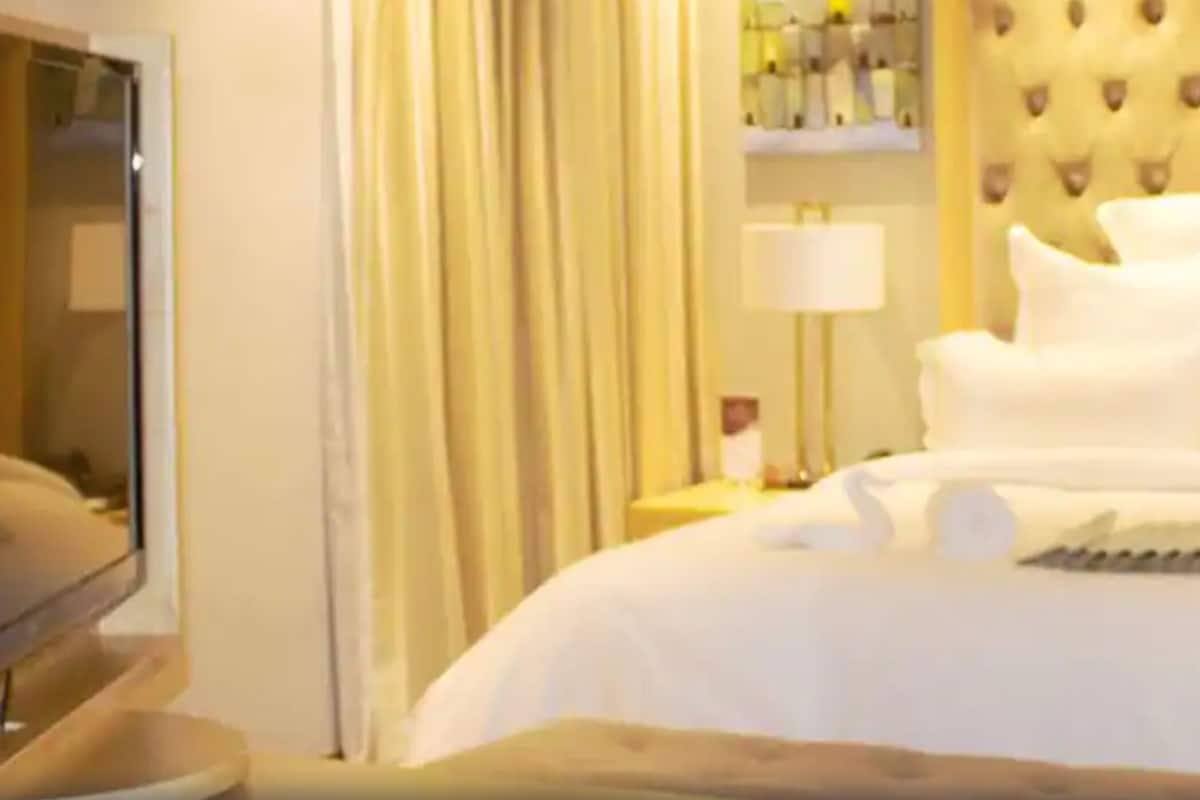 A hotel room with a large bed, a television, and a tufted headboard.