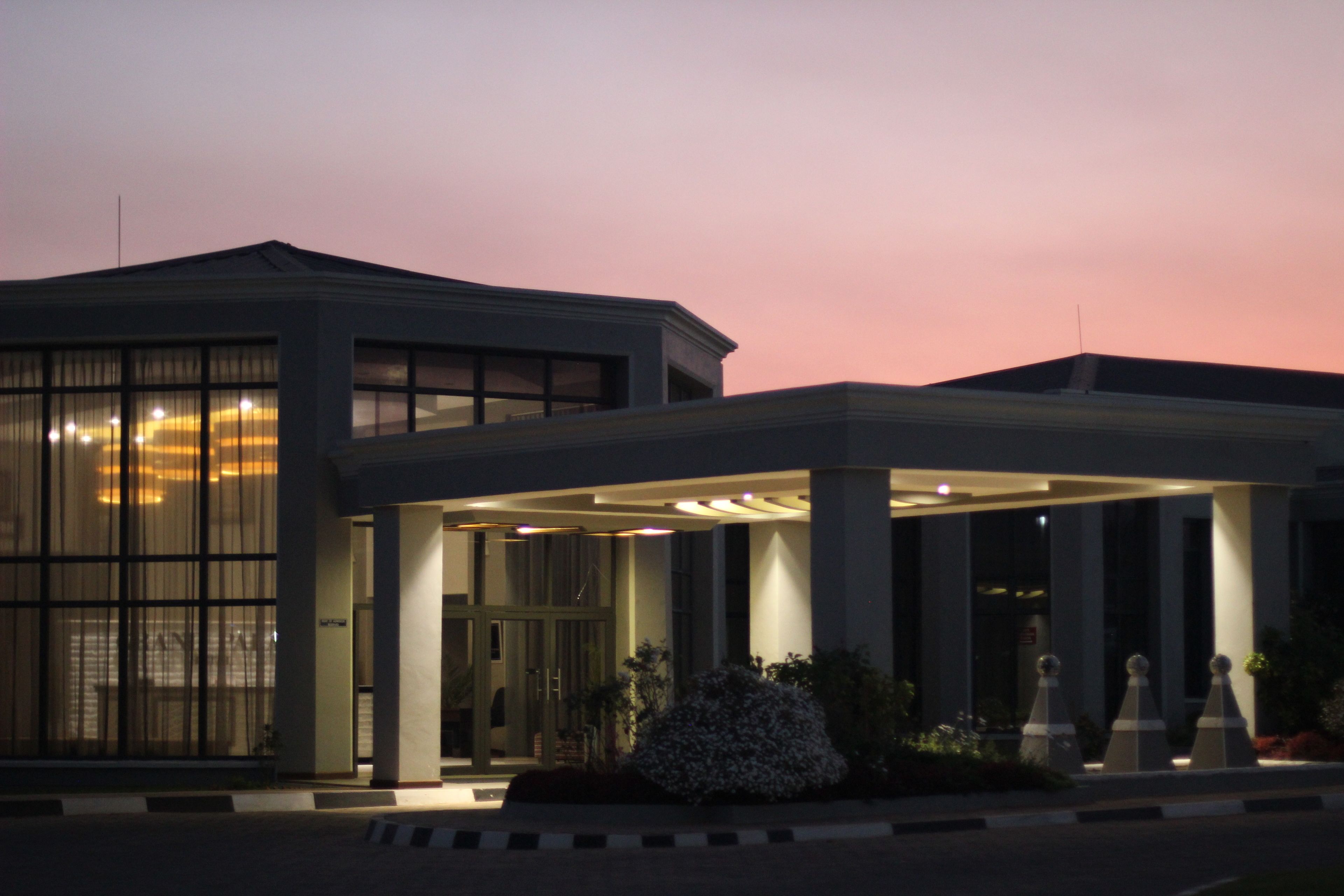 A modern building with a covered entrance, large windows, and a well-lit facade.