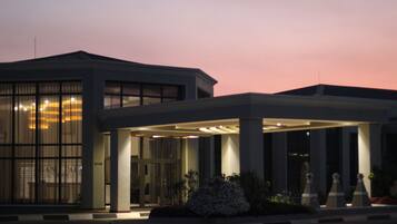 A modern building with a covered entrance, large windows, and a well-lit facade.