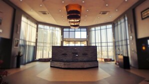 A spacious lobby with a central seating area, large windows, and a modern ceiling design. - Grand Palace Hotel (Mzuzu)