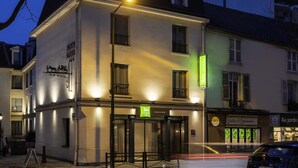 Ein Hotel mit einer klassischen Fassade, einem gut sichtbaren Eingang und einem Schild für 'ibis Styles', das ein Restaurant in der Nähe kennzeichnet.