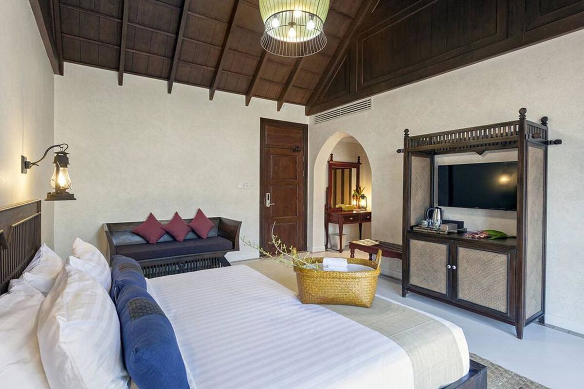 A bedroom with a bed, bedside table, lamp, TV, and a wardrobe.