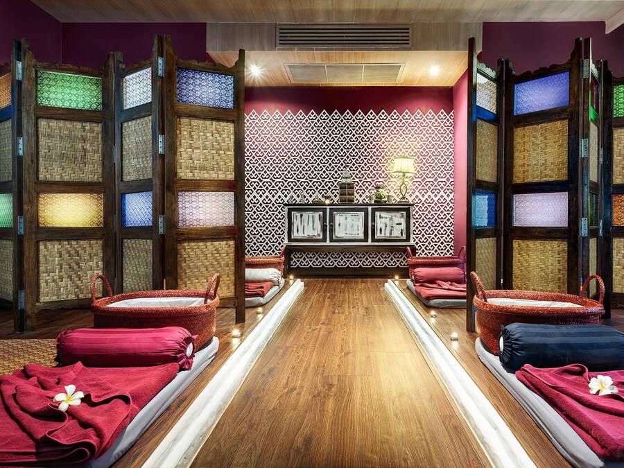A room with a wooden floor, red towels, and a patterned wall.