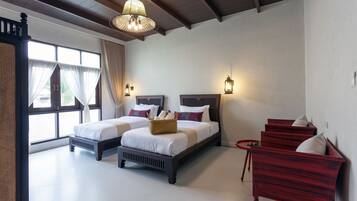 A bedroom with two beds, a wooden bench, and a small table.