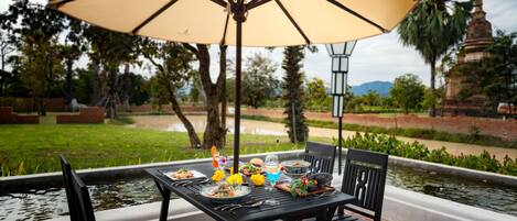 An outdoor dining area with a table, chairs, and a large umbrella.