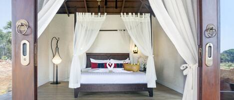 A four-poster bed with white bedding, a bedside lamp, and a basket on the bed.