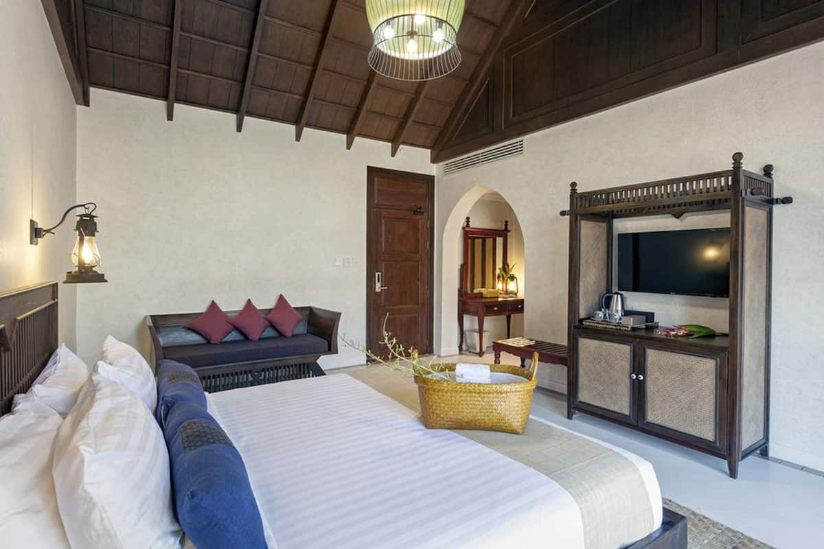 A hotel room with a large bed, a television, a wooden cabinet, and a ceiling light fixture.