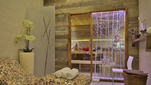 Un cuarto de spa con una camilla de masaje, una mampara de vidrio y una pared de madera.