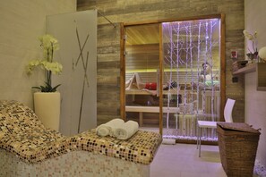 A spa room with a massage table, a glass partition, and a wooden wall. - Atera Business Suites (Belgrade)