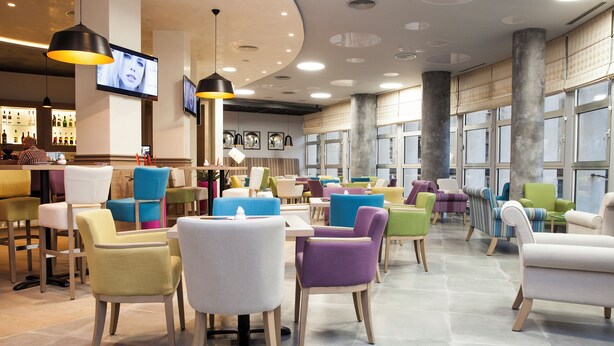A modern interior with a bar area, multiple seating options, and large windows. - Atera Business Suites (Belgrade)