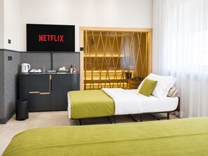 A hotel room with a bed, a TV mounted on the wall, a minibar, and a window with curtains. - Atera Business Suites (Belgrade)