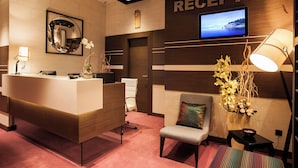 Una zona de recepción con un mostrador de madera, una pantalla de televisión, un espejo y una silla con cojín.