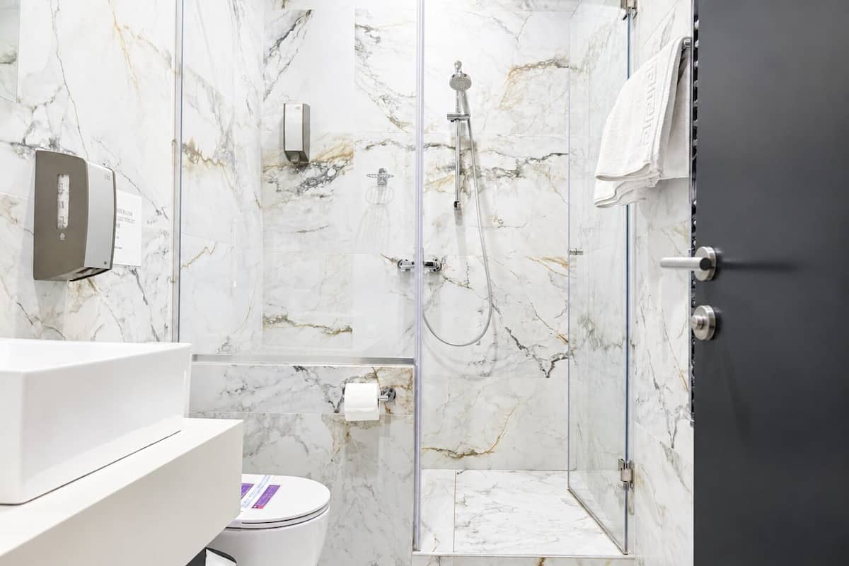 A modern bathroom with a marble shower, a toilet, and a sink.